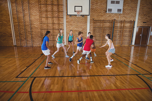 Determined high school kids playing basketball in the court