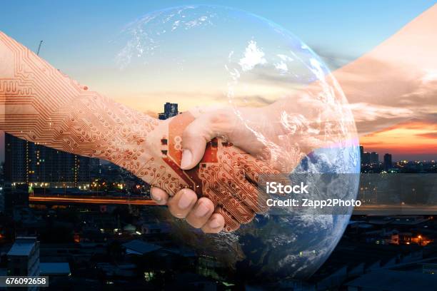 Industry 40 Internet Of Things And Digital Disruption Concept Double Exposure Of Shaking Hands Of Male People And Robot Circuit Electronic Hand With Construction Building And Earth Furnished By Nasa Stock Photo - Download Image Now