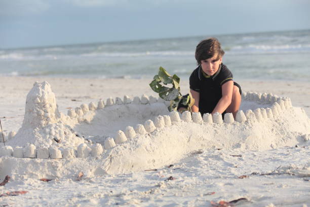 istock Boy at the beach builds sandcastle. 676092748