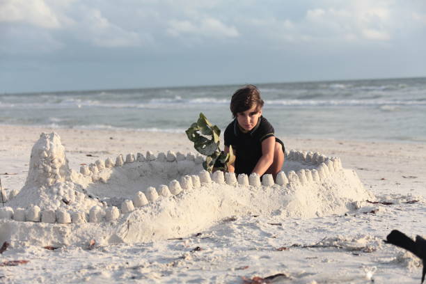 istock Boy at the beach builds sandcastle. 676094782