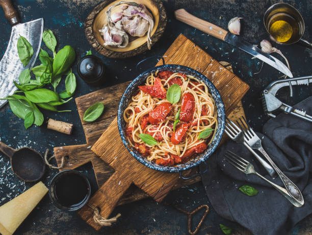 spaghetti al pomodoro e basilico in piatto su tavola di legno - garlic cooking oil cutting board horizontal foto e immagini stock