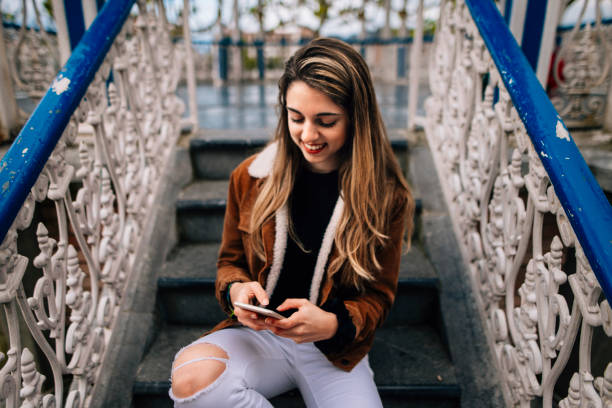 Young woman texting A young woman texting with her mobile phone. escribir stock pictures, royalty-free photos & images