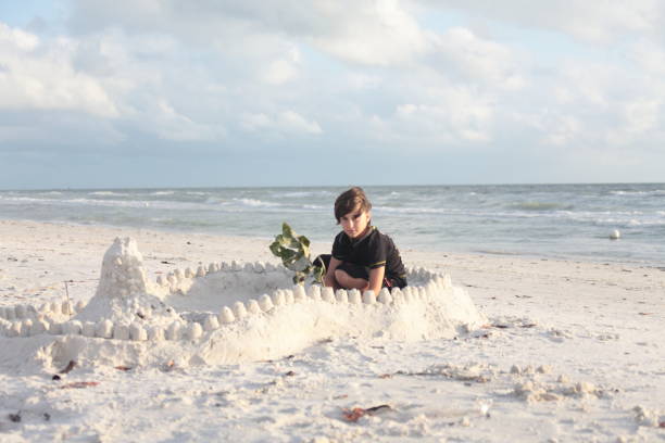istock Boy at the beach builds sandcastle. 676117080