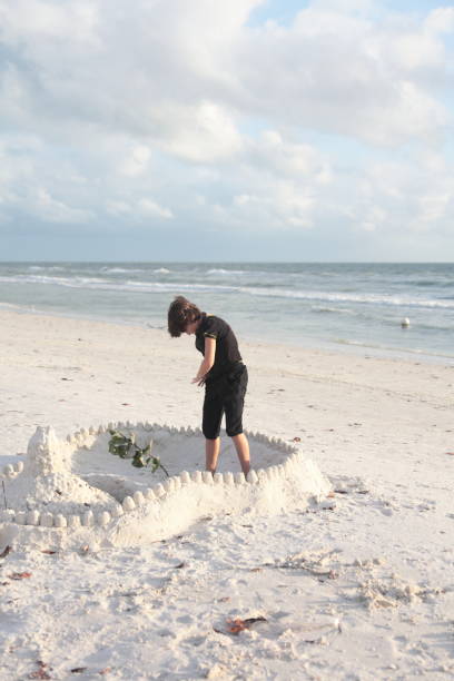 istock Boy at the beach builds sandcastle. 676126310