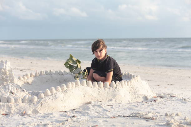 istock Boy at the beach builds sandcastle. 676126334