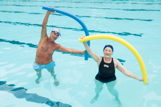 istock Senior couple exercising with pool noodle in swimming pool 676128924