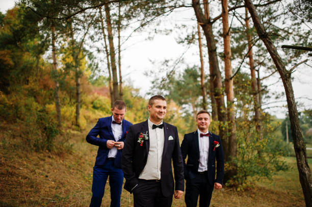 istock Groom with best mans on bow tie at autumn pine wood. 676137788