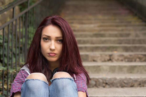 Sad lonely girl sitting on stairs stock photo