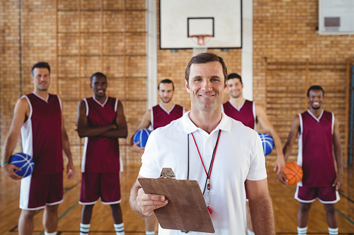 Portrait of smiling coach and basketball player standing in the court