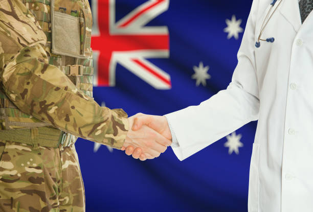 Military man in uniform and doctor shaking hands with national flag on background - Australia stock photo