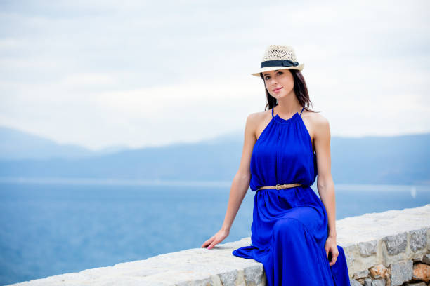 photo of beautiful young woman sitting on the stairs  in greece - beach stone wall one person imagens e fotografias de stock