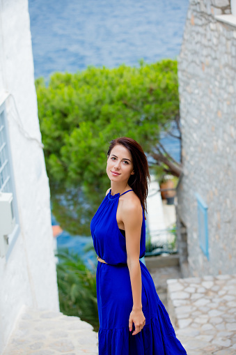 photo of beautiful young woman standing on the stairs near the houses in Greece