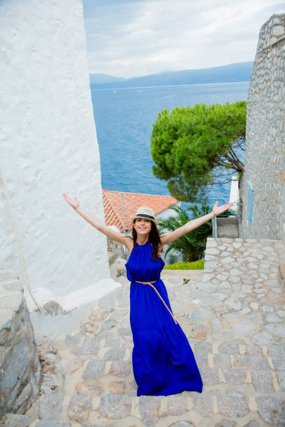 photo of beautiful young woman standing on the stairs in the middle of the street in greece - beach stone wall one person imagens e fotografias de stock