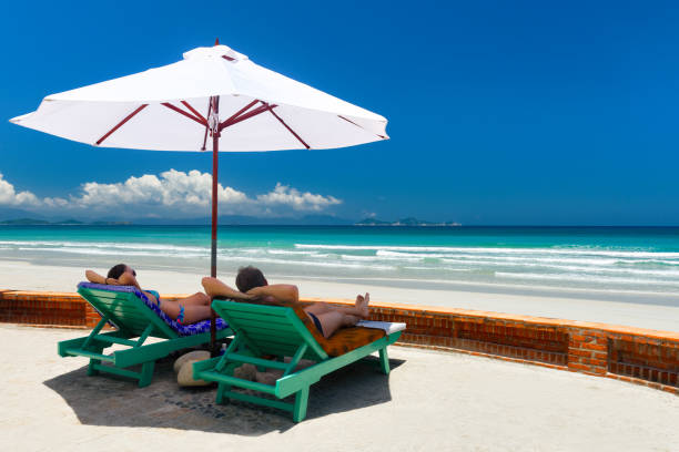 istock Couple on a tropical beach on deck chairs under a white umbrella. 676219330