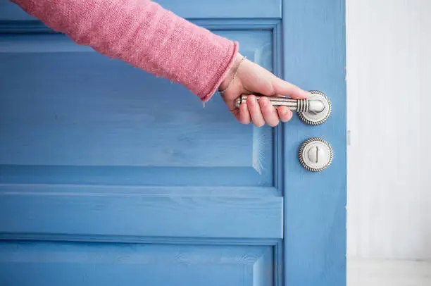 man holding a metal pen in an open wooden door blue