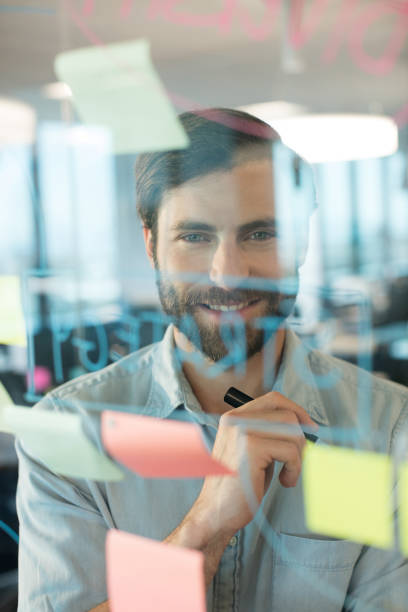 istock Smiling businessman looking through plans written on glass 676234472
