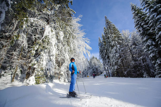 Happy woman skier on a ski slope in the forest Full length portrait of happy skier on a ski slope in the forest with big beautiful trees covered in snow. Winter sports concept. Bukovel, Ukraine bukovel ski resort ukraine stock pictures, royalty-free photos & images
