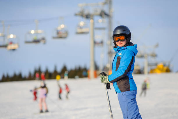 Woman skier skiing downhill at ski resort against ski-lift Close-up portrait of young happy woman skier at the ski resort on a sunny day against ski-lift. Girl is wearing blue jacket, helmet and goggles. Carpathian Mountains, Bukovel bukovel ski resort ukraine stock pictures, royalty-free photos & images