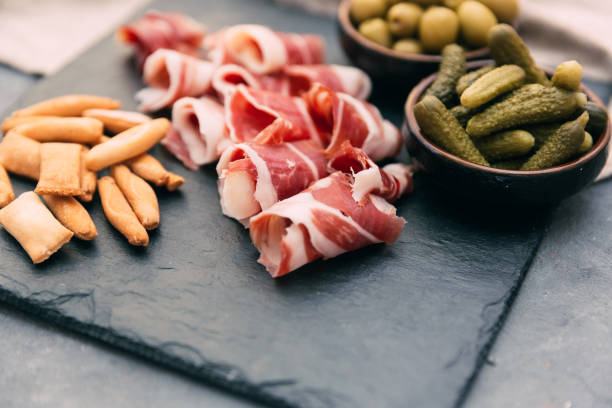 istock Typical spanish tapas concept. Concept include variety slices jamon, chorizo, salami, bowls with olives, peppers, anchovies, spicy potatoes 676285342