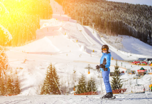Girl skier against ski slopes and ski-lift on background Portrait of young happy girl skier against ski slopes and ski-lift on background. Woman is wearing helmet skiing glasses gloves and blue ski suit. Winter sports concept. Carpathian Mountains, Bukovel bukovel ski resort ukraine stock pictures, royalty-free photos & images