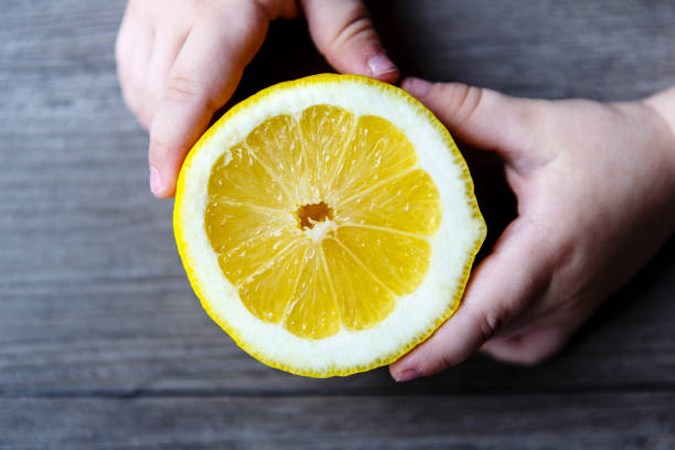 istock beautiful fresh yellow lemon in child hands on the wooden rustic table 676310320