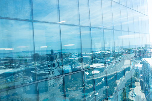 Full frame shot of office building exterior with reflection of city against sky