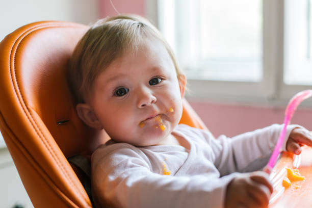 niña feliz en silla alta - baby carrot fotografías e imágenes de stock