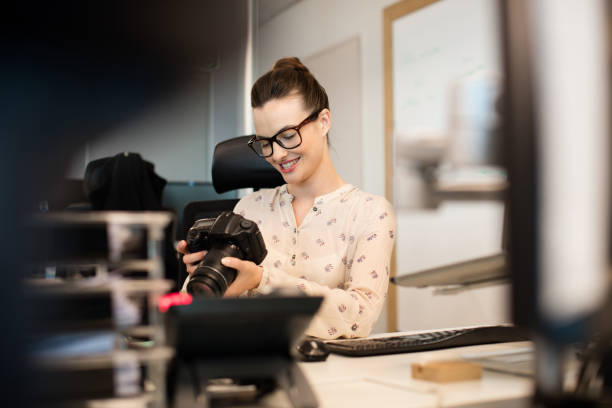 istock Smiling female photographer using camera at creative office 676324424