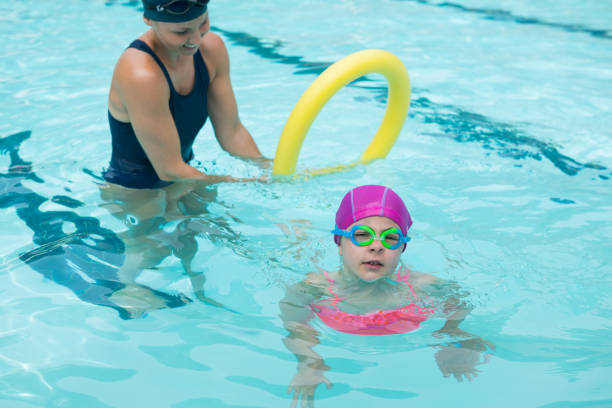 istock Female instructor training young girl in pool 676324640