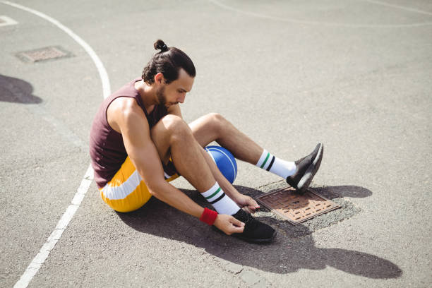 istock Basketball player tying shoe laces while sitting 676326348