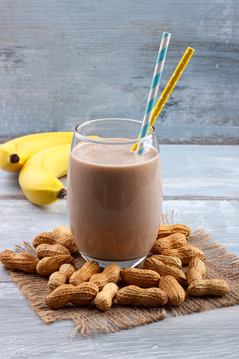 Peanut butter, banana, oat smoothie on blue wooden background, selective focus