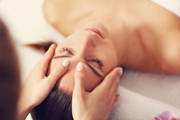 schöne frau, die erste massage im spa - massaging spa treatment stone massage therapist stock-fotos und bilder