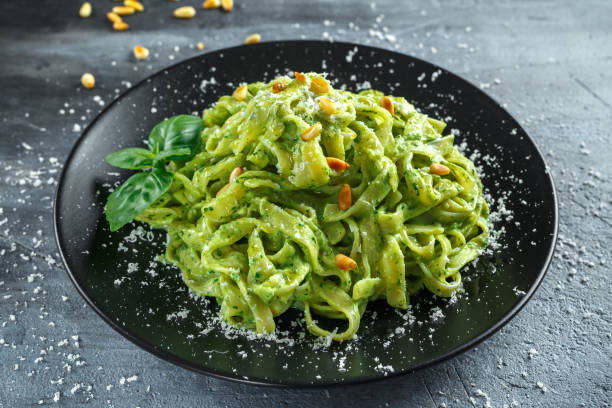 istock Tagliatelle pasta with pesto sauce, pine nuts and parmesan on black plate. 676364362