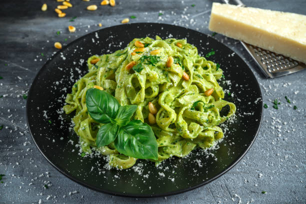 istock Tagliatelle pasta with pesto sauce, pine nuts and parmesan on black plate. 676365526