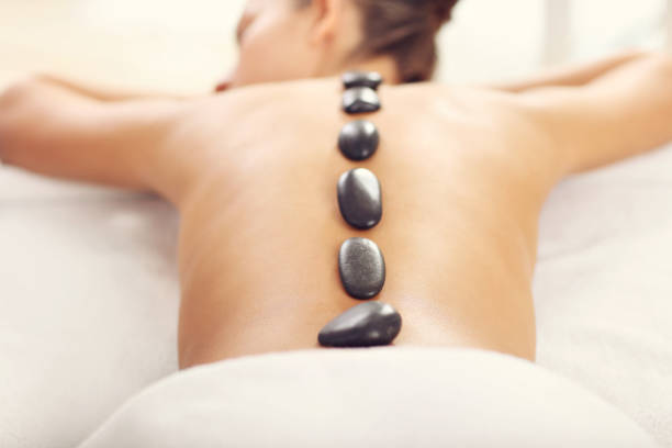 schöne frau, die immer-stone-massage im spa - massaging spa treatment stone massage therapist stock-fotos und bilder