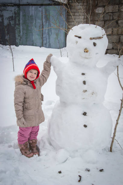 istock happy girl and snowman 676367372