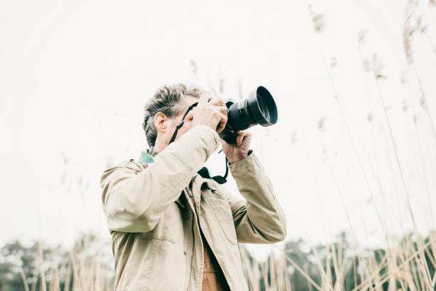 istock Man taking pictures of nature. Standing between reed. 676404508