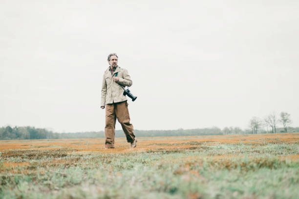 istock Man with camera walking over grassy land. 676404530