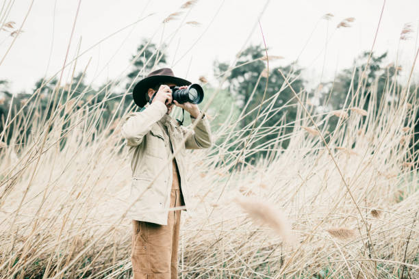 istock Man with hat standing between reed photographing nature. 676404764