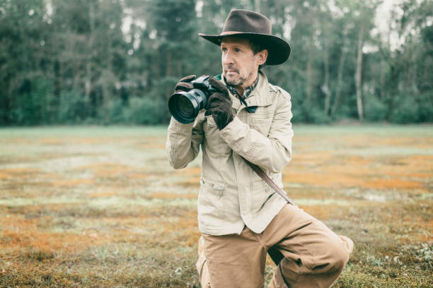 istock Explorer with hat in the field holding camera. 676404834