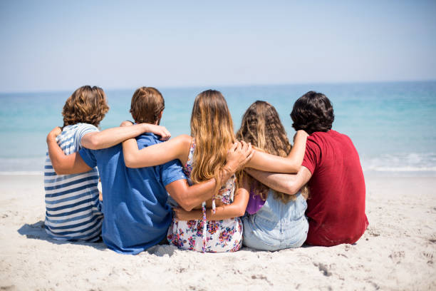 istock Friends sitting with arms around at beach 676410368