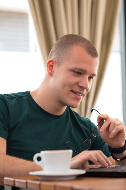 istock Young man sitting, looking at laptop and  and drinking coffee 676419352