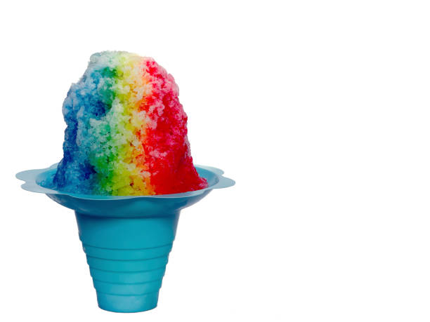 Rainbow Hawaiian Shave ice or snow cone in a blue flower shaped cup on a white background.