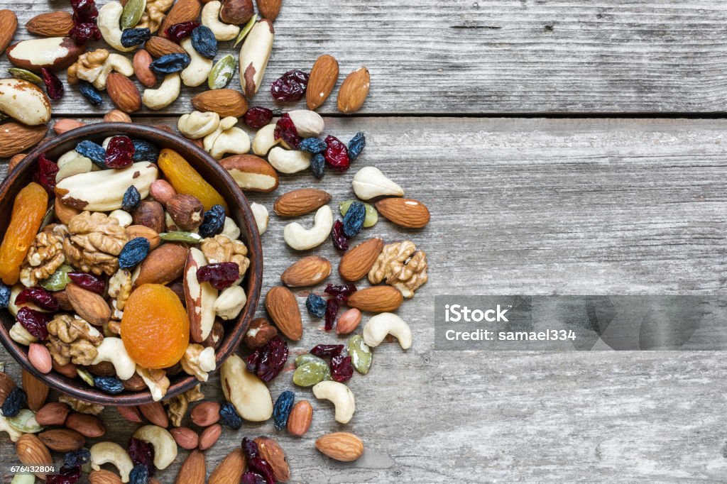 nuts and dried fruits in a bowl over rustic wooden table nuts and dried fruits in a bowl over rustic wooden table. top view with copy space. healthy food Nut - Food Stock Photo