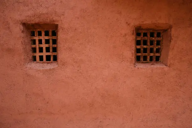 Two windows on rustic old red orange mud clay wall in Abyaneh, Iran