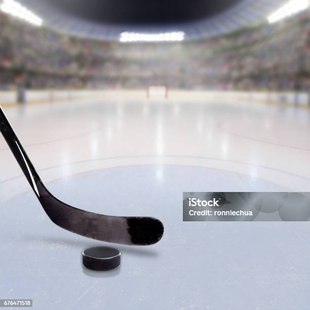 Hockey Stick And Puck On Ice Of Crowded Arena Stock Photo - Download Image Now - Hockey Stick, Stadium, Hockey Puck