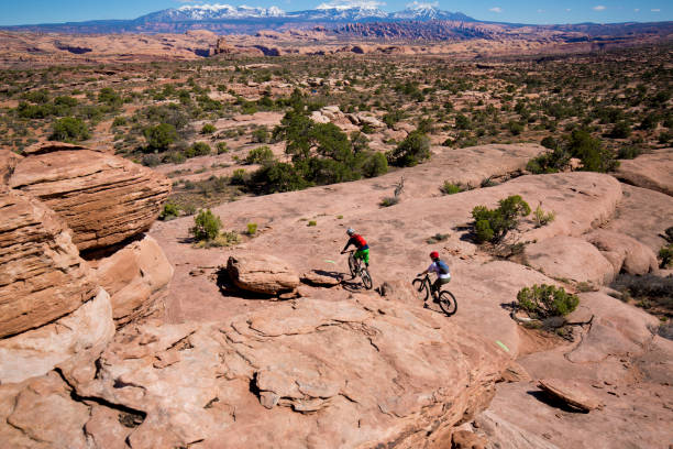 un uomo guida una donna in un giro in mountain bike di fondo a moab, utah, usa. - 5552 foto e immagini stock