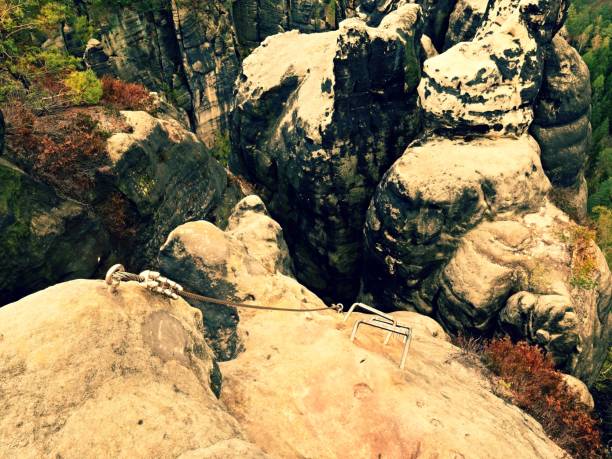 istock Climbers ladder. Iron twisted rope fixed in block by screws snap hooks. The rope end anchored into sandstone rock. 676487502