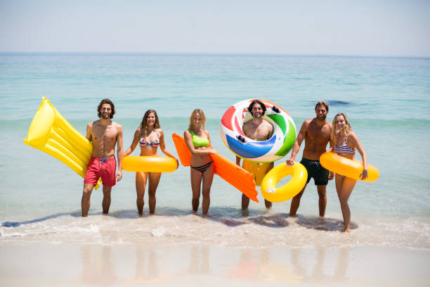 istock Friends with inflatable rings and pool rafts on seashore 676513502