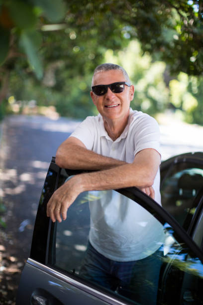 istock Smiling man leaning on car door 676554426